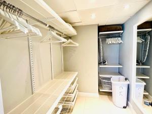 a walk in closet with white shelving at Hollywood on Beach Apartment in Hollywood +70 photos