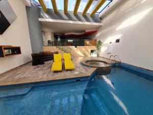 a swimming pool with yellow cushioned chairs and a table in a building at Hotel Alcampo in Querétaro
