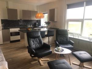 a kitchen with black chairs and a table and a counter at Grønnegade - tæt på Esbjerg C in Esbjerg