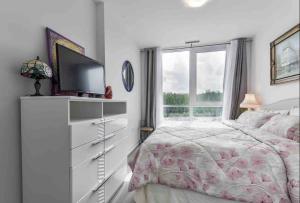 1 dormitorio con 1 cama y vestidor con TV en Aquarius 2 Bedroom Condo Friday Harbour, en Innisfil