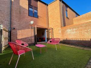 three pink chairs sitting on the grass in front of a brick building at 2 Bedroom House with Garden Next to River Tees in Stockton-on-Tees