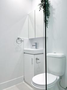 a white bathroom with a toilet and a sink at One on Harris Apartments in Wellington Point