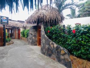 a building with a stone wall and a straw umbrella at Tres Palmas in Montañita