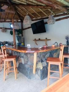 a stone bar in a room with chairs and a tv at Tres Palmas in Montañita