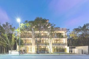 een hoog wit gebouw met een straatlicht ervoor bij HIGHLINE 101 By SANDY POWERFUL in Tulum