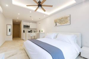 een slaapkamer met een wit bed en een plafondventilator bij HIGHLINE 101 By SANDY POWERFUL in Tulum
