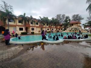 a group of people sitting around a swimming pool at Seri Indah Resort in Kuala Terengganu