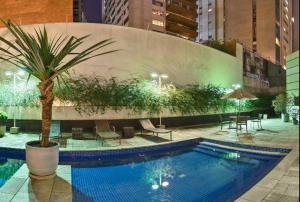 una piscina con una palmera al lado de un edificio en Hotel na Alameda Lorena - Jardins, en São Paulo
