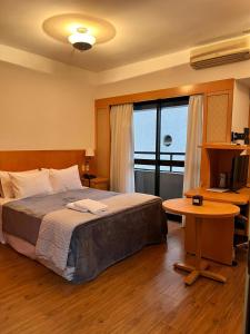 1 dormitorio con cama, mesa y ventana en Hotel na Alameda Lorena - Jardins, en São Paulo