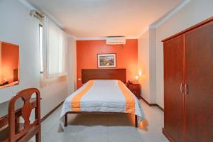 a bedroom with a bed with an orange wall at Sol Del Sur Hotel in Huaquillas