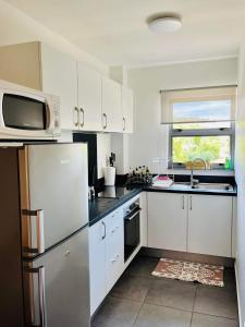 a kitchen with a refrigerator and a microwave at Tehautahi Cozy Lodge in Papeete
