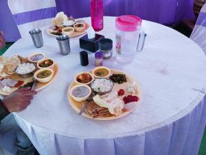 Biały stół z talerzami żywności w obiekcie Mhatre Cottage Alibag Mani w mieście Alibag