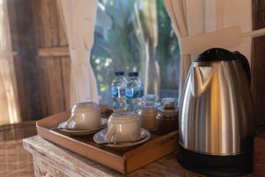 a wooden tray with a coffee maker and bottles of water at Umah Capung Sebatu Villas in Tegalalang