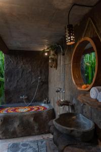 La salle de bains est pourvue d'une grande baignoire et d'un lavabo. dans l'établissement Umah Capung Sebatu Villas, à Tegalalang