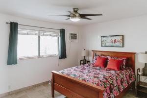 Schlafzimmer mit einem Bett mit roten Kissen und einem Deckenventilator in der Unterkunft Holualoa Garden 103 in Kailua-Kona
