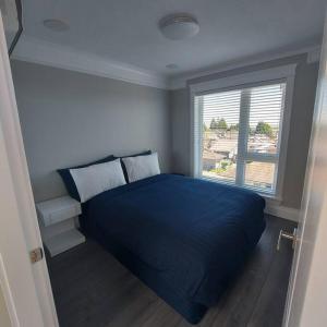 um quarto com uma cama azul e uma janela em Beautiful Bright 3 Bed Townhouse em Vancouver