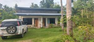 a white car parked in front of a house at Andnindot garden resort in Anda