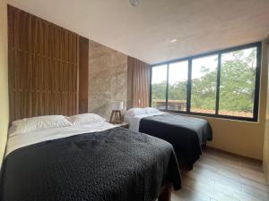 a bedroom with two beds and a large window at Cabaña de la Cascada in Mazamitla