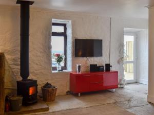 a living room with a red dresser and a fireplace at The Calving Shed in Neilston