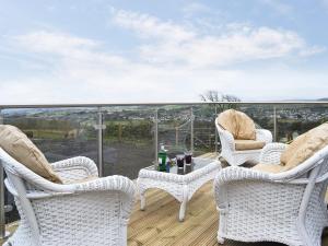 a patio with three chairs and a table on a balcony at The Calving Shed in Neilston