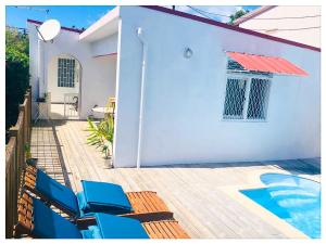 a white house with blue chairs and a swimming pool at Villa GAIA in Les Trois-Îlets