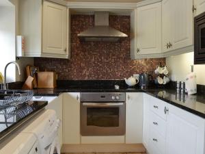 a kitchen with white cabinets and a stove top oven at Clematis Cottage in Burnsall