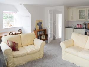 a living room with two white couches and a kitchen at Old Manse Annex in Town Yetholm