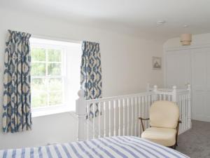 a bedroom with a bed and a chair and a window at Old Manse Annex in Town Yetholm