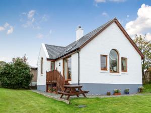 a white house with a picnic bench in the yard at Seabird Cottage in Broadford