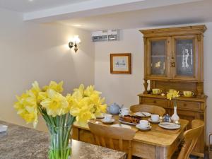 a dining room with a table with yellow flowers in a vase at Honey Cottage in Newland