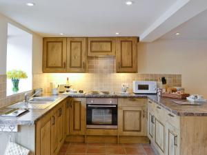 a kitchen with wooden cabinets and a sink and a microwave at Honey Cottage in Newland