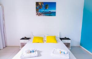 1 dormitorio con cama blanca y almohadas amarillas en La Villa Soleil :), en Sainte-Anne