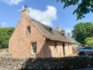 an old brick house with a stone wall at The Thatched Cottage in St Andrews