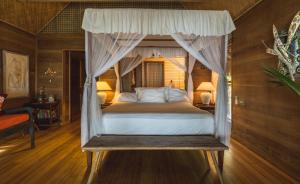 - une chambre avec un lit à baldaquin dans l'établissement Fare Ahuna, à Bora Bora