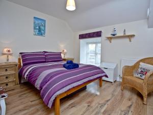 a bedroom with a purple bed with a blue stuffed animal on it at Applebee Cottage in Bridport