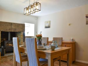 a dining room with a table and chairs and a fireplace at Meadow View in Youlgreave