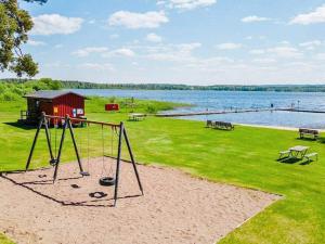 een park met een schommel en een meer bij Holiday home HÖKERUM II in Hökerum