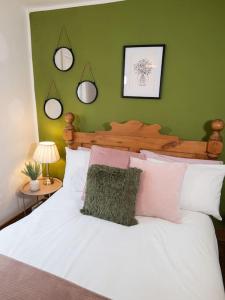 a bedroom with a white bed with a green wall at Cosy Cottage in Central Reading Free Parking & Fast Wifi in Reading