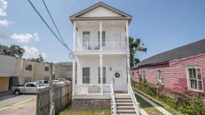 ein weißes Haus mit einer Veranda und einem rosa Gebäude in der Unterkunft Vibrant Luxury Downtown Loft 2833 NOLA in New Orleans