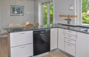 a kitchen with white cabinets and a black dishwasher at Stunning Home In Frrup With House Sea View in Tårup