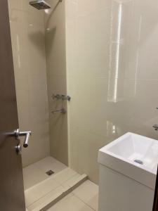 baño blanco con ducha y lavamanos en Departamento Alsina al mil en Salta