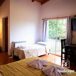 a bedroom with two beds and a large window at Posada Inguz in Villa Berna