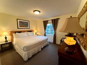 um quarto com uma cama, um candeeiro e uma janela em Bayshore Waterfront Inn em Ucluelet