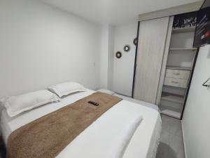 Un dormitorio con una cama blanca con una toalla. en Apartamento Almendros Home, en Santa Rosa de Cabal