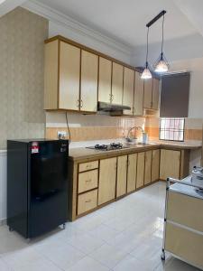 Comfy Sutera Seberang Jaya في Kampong Belah Dua: مطبخ مع ثلاجة سوداء ودواليب خشبية