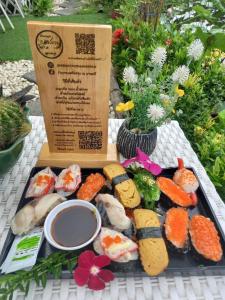 ein Tablett mit Sushi und Gemüse auf dem Tisch in der Unterkunft Ban Ing Suan in Samutprakarn