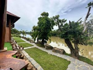 a garden with rocks and trees next to a body of water at Floor river view in Cat Tien