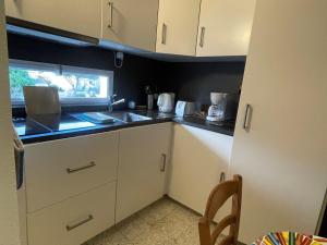 małą kuchnię z białymi szafkami i zlewem w obiekcie Charmant appartement climatisé Proche des Thermes - FR-1-503-166 w mieście Balaruc-les-Bains