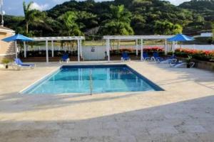 a swimming pool with blue chairs and umbrellas at Snooze at Oceanpointe in Lucea