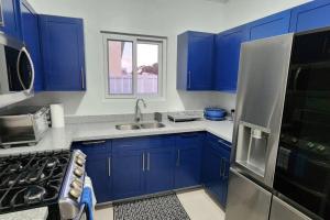 uma cozinha com armários azuis, um lavatório e um frigorífico em Snooze at Oceanpointe em Lucea